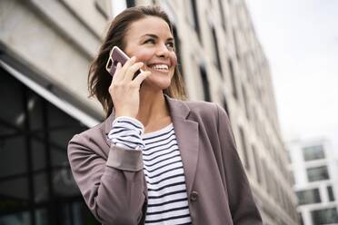 Glückliche Geschäftsfrau beim Telefonieren in der Stadt - PNEF01851