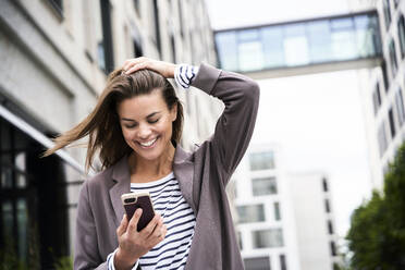 Happy businesswoman using smartphonein the city - PNEF01852