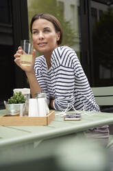 Woman having a drink at an outdoors cafe - PNEF01863