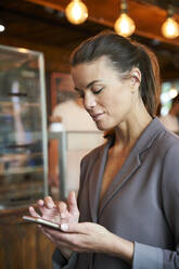 Geschäftsfrau benutzt Smartphone in einem Café - PNEF01878