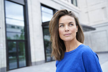 Portrait of attractive brunette woman wearing blue top in the city - PNEF01892