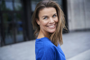 Portrait of attractive brunette woman wearing blue top in the city - PNEF01896