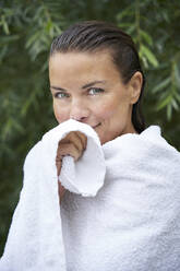 Porträt einer Frau mit nassen Haaren, eingewickelt in ein Handtuch, in der Natur - PNEF01927