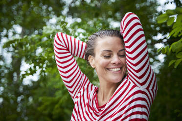 Portrait of happy woman with wet hair wearing striped top in nature - PNEF01932