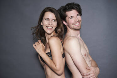 Porträt eines glücklichen, halb angezogenen Paares, Rücken an Rücken - PNEF01964