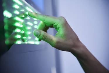 Detail des Fingers, der den grünen LED-Touchscreen berührt - PNEF01968