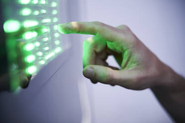 Detail des Fingers, der den grünen LED-Touchscreen berührt - PNEF01969