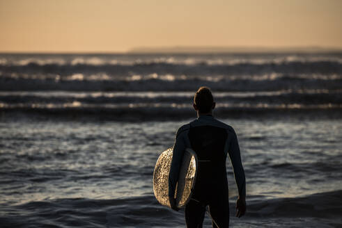 Ein Surfer, der die Wellen am Croyde Beach in Devon, England, Vereinigtes Königreich, Europa betrachtet - RHPLF08658