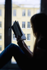 Teenage girl (16-17) reading book by window - FOLF10330