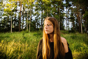 Porträt einer jungen Frau im Wald bei Sonnenuntergang - FOLF10358