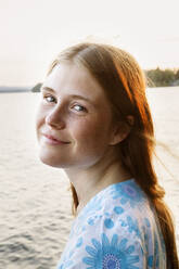 Porträt einer jungen Frau mit See im Hintergrund - FOLF10360