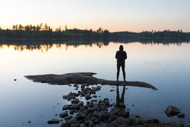 Mann steht auf einem Felsen im See bei Sonnenuntergang - FOLF10470