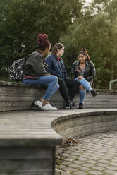 Teenage girls using smart phone in park - FOLF10559