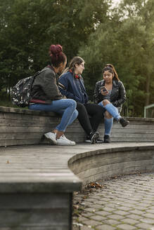 Teenager-Mädchen benutzen ihr Smartphone im Park - FOLF10559