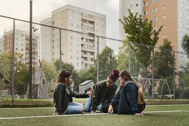 Teenage girls using smart phone on tennis court - FOLF10562