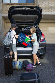 Jungen laden Koffer aus dem Kofferraum aus - FOLF10593