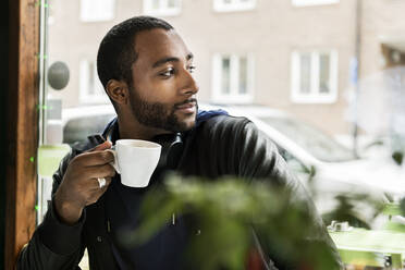 Junger Mann mit einer Tasse Kaffee in einem Cafe - FOLF10597