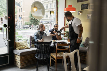 Barista bedient junge Männer in einem Café - FOLF10605