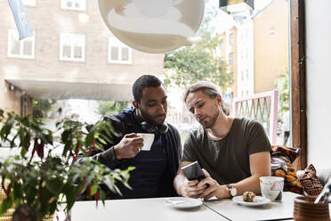 Junge Männer sitzen zusammen in einem Cafe - FOLF10610