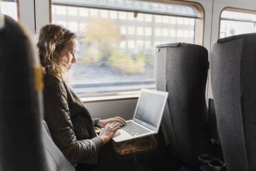 Young woman commuter on train using laptop - FOLF10653