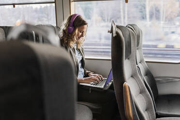 Young woman commuter on train using laptop - FOLF10656