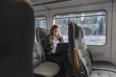 Young woman commuter on train using laptop - FOLF10657