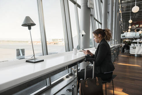 Frau benutzt Smartphone im Flughafen - FOLF10664