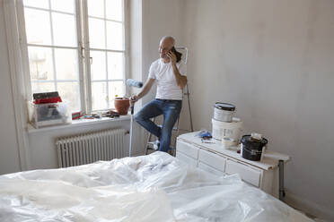 Mittlerer Erwachsener, der während der Wohnungsrenovierung mit seinem Handy telefoniert - FOLF10690