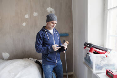 Mid adult man looking at tablet PC during apartment renovation - FOLF10692
