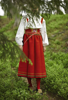 Frau in rotem Kostüm auf einem Feld - FOLF10703