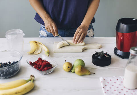 Woman cutting banana for a smoothie stock photo