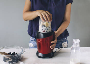 Frau macht Smoothie in einem Mixer - MOMF00755