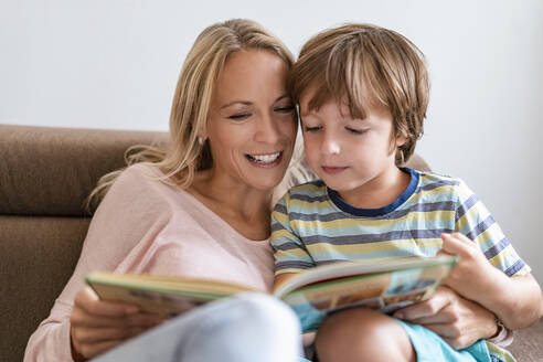 Mutter und Sohn lesen zusammen ein Buch auf der Couch zu Hause - DIGF08133