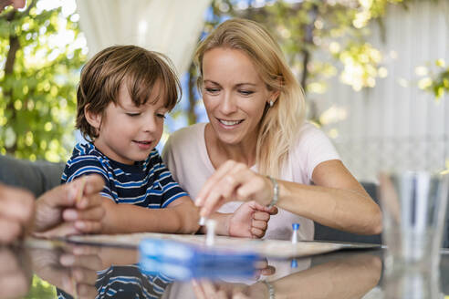 Mutter und Sohn spielen ein Brettspiel auf der Terrasse - DIGF08135