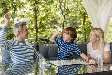 Glücklicher Vater und Sohn, die sich nach einem gewonnenen Spiel auf der Terrasse die Hände reichen - DIGF08141