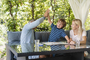 Glücklicher Vater und Sohn, die sich nach einem gewonnenen Spiel auf der Terrasse die Hände reichen - DIGF08142