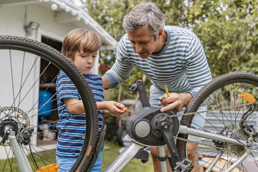 Vater und Sohn reparieren ein Fahrrad im Garten - DIGF08148