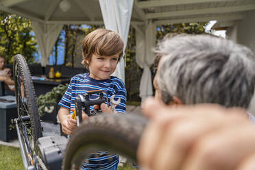 Father and son repairing a bicycle in garden - DIGF08151