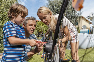 Family repairing a bicycle together in garden - DIGF08154