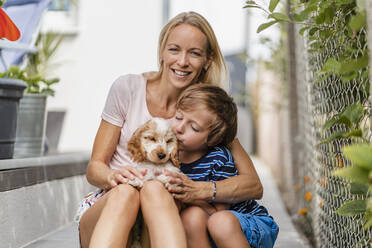 Porträt von Mutter und Sohn kuscheln mit niedlichen Hund Welpen - DIGF08163
