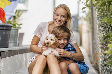 Porträt von Mutter und Sohn kuscheln mit niedlichen Hund Welpen - DIGF08164