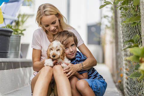 Porträt von Mutter und Sohn kuscheln mit niedlichen Hund Welpen - DIGF08165