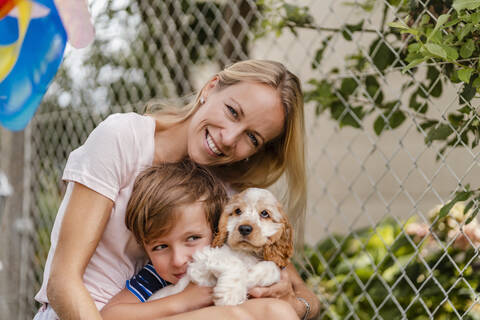 Porträt von Mutter und Sohn kuscheln mit niedlichen Hund Welpen, lizenzfreies Stockfoto