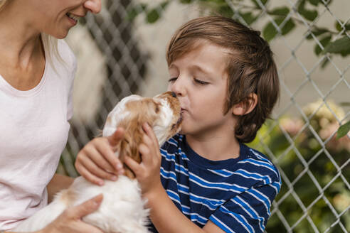 Mutter und Sohn kuscheln mit süßem Hundewelpen - DIGF08167