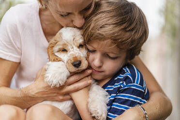 Mutter und Sohn kuscheln mit süßem Hundewelpen - DIGF08168