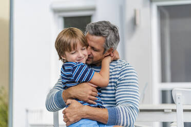 Father and son cuddling in garden - DIGF08171