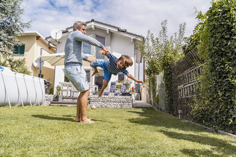 Vater spielt mit Sohn im Garten, lizenzfreies Stockfoto