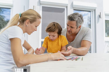 Father, mother and son doing homework together on terrace - DIGF08177