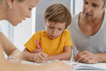 Vater, Mutter und Sohn machen gemeinsam Hausaufgaben auf der Terrasse - DIGF08178