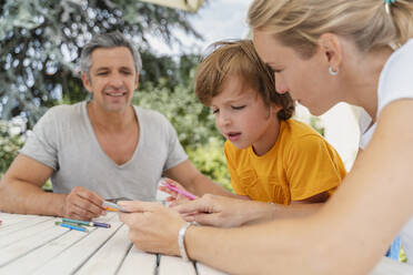 Father, mother and son doing homework together on terrace - DIGF08182